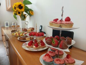 A sideboard covered with plates of strawberries and baked goods.