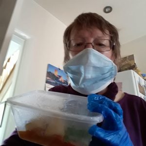 Soroptimist wearing mask and gloves with tupperware containing meal