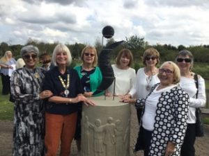 Group of smiling women around Soroptimist sculpture