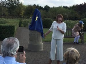 Woman in white trouser suit about to unveil statue