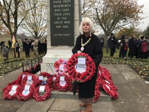 Woman holding poppy wreath in front of memorial