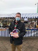 Man standing with prize outside tombola stall