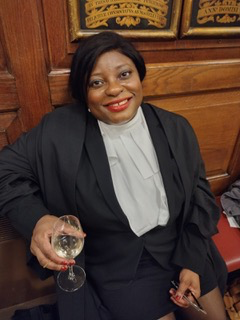 Woman of colour in barrister's outfit holding a glass of wine