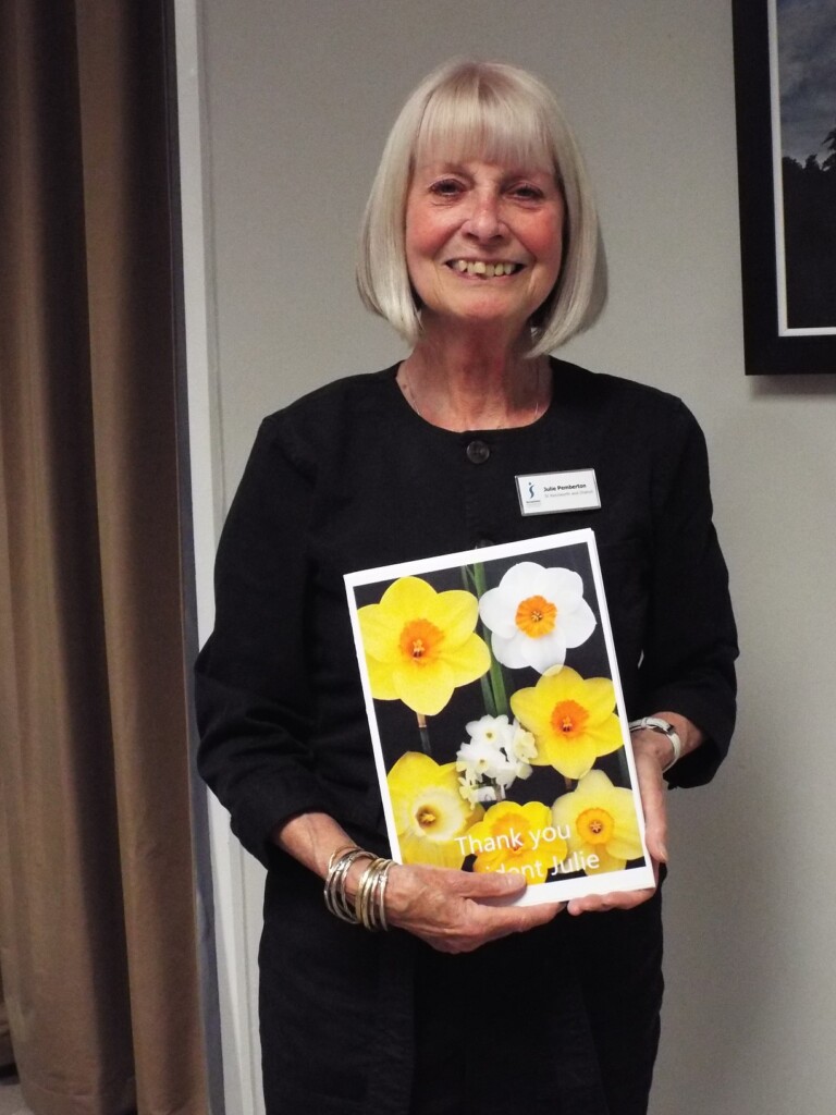Grey haired woman holding a card with daffodils on