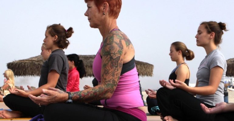 Photo of women attending a beach side yoga class