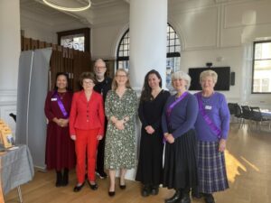 Leading Soroptimists, each with a purple sash for International Women's Day, with the event's keynote speakers and performers. 