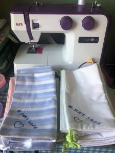 A sewing machine with some finished scrubs bags 