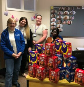 Swindon Soroptimist Jackie Webb with Carrie, Kerry and Ella from the Nelson Trust Women’s Centre all stand behind a stack of boxed Easter eggs