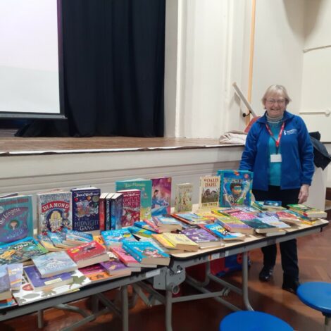 Club Secretary Jackie stands at the side of a table filled with books