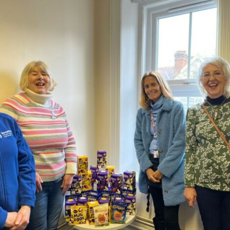 Swindon Soroptimists Jackie Webb, Alison Millin, Gillian Reed with Tracey from the Nelson Trust, all caught in a moment of group laughter. They're standing around a small table, covered in boxed Easter eggs.