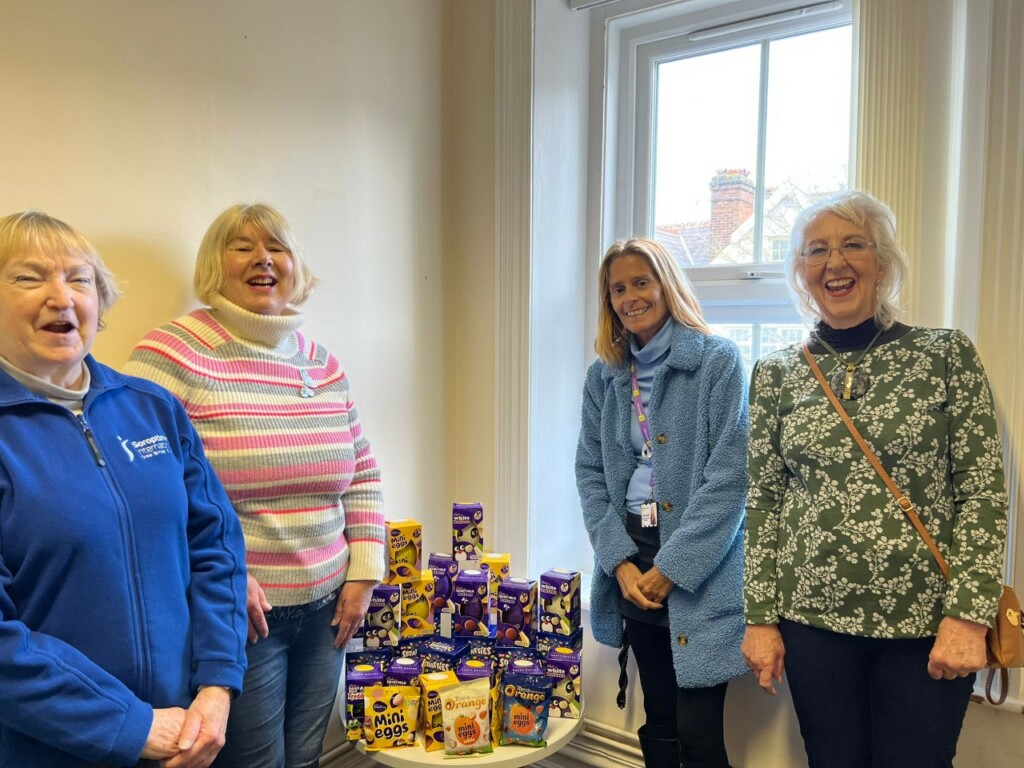 Swindon Soroptimists Jackie Webb, Alison Millin, Gillian Reed with Tracey from the Nelson Trust, all caught in a moment of group laughter. They're standing around a small table, covered in boxed Easter eggs.
