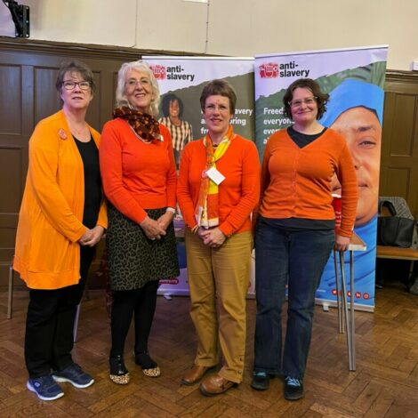 Members of Swindon Soroptimists wearing orange, while standing next to a display for Anti-Slavery International