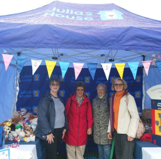 Four Soroptimists standing inside a gazebo with the Julia's House logo on its canopy