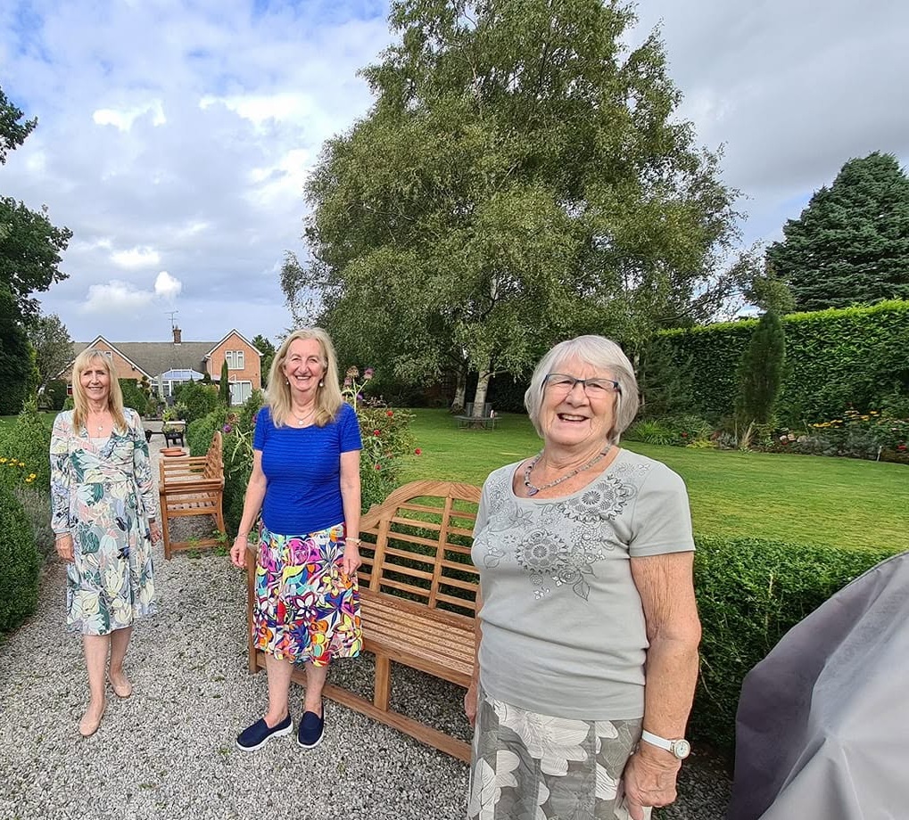 3 of our members stand in a garden.